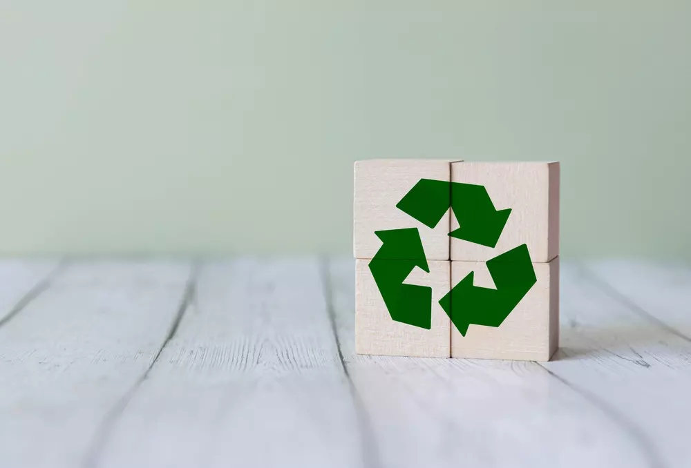 Blocos de madeira formando o símbolo de reciclagem, ilustrando a circularidade na ideia de reciclagem de baterias e sustentabilidade ambiental.