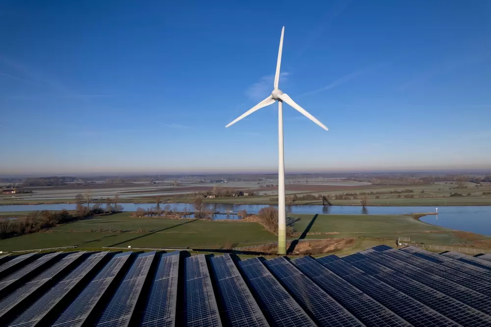 parque de energia renovável com uma turbina eólica ao fundo e painéis solares na frente