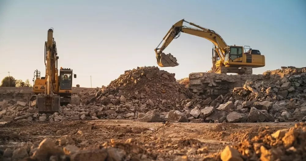 Escavadeiras operando em obra de construção civil, movimentando pedras e terra 
