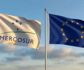 Bandeiras do Mercosul e da União Europeia ao vento, simbolizando a integração e cooperação regional na América do Sul e na Europa.