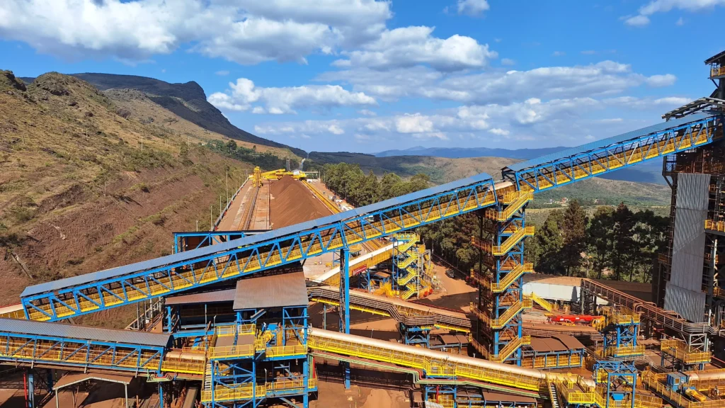 Mina Capanema da Vale mostrando estruturas de carregamento e transporte em meio a um cenário de montanhas e céu com nuvens.