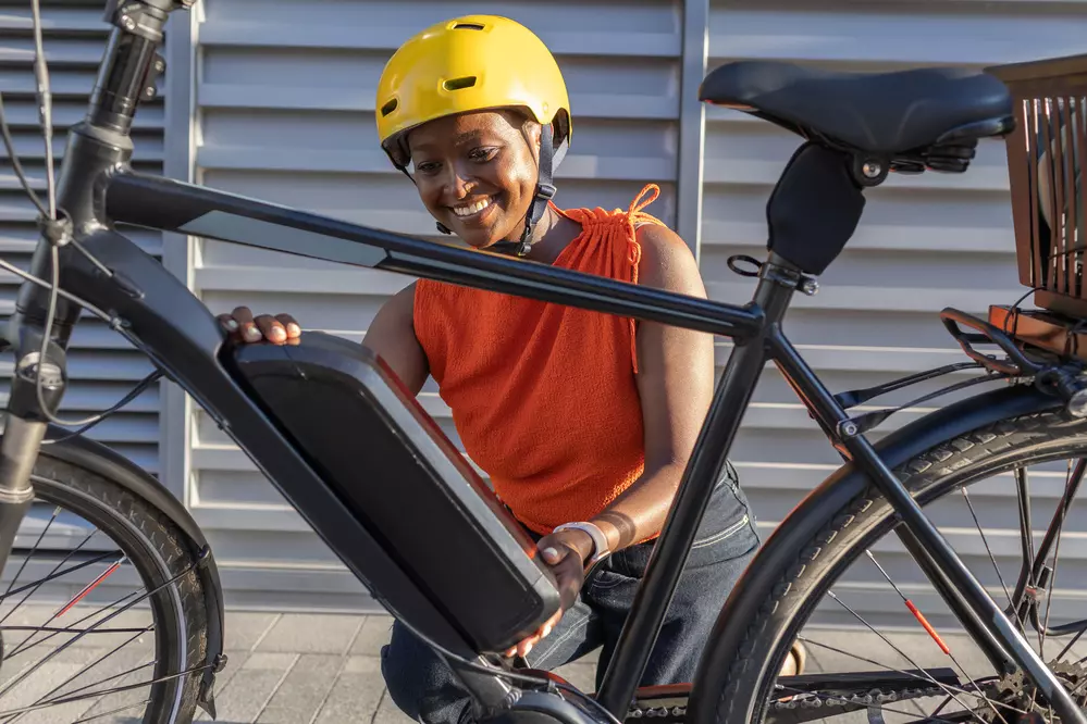 Mulher feliz ajustando bicicleta elétrica, destacando a importância da micromobilidade elétrica para transporte sustentável e eficiente.