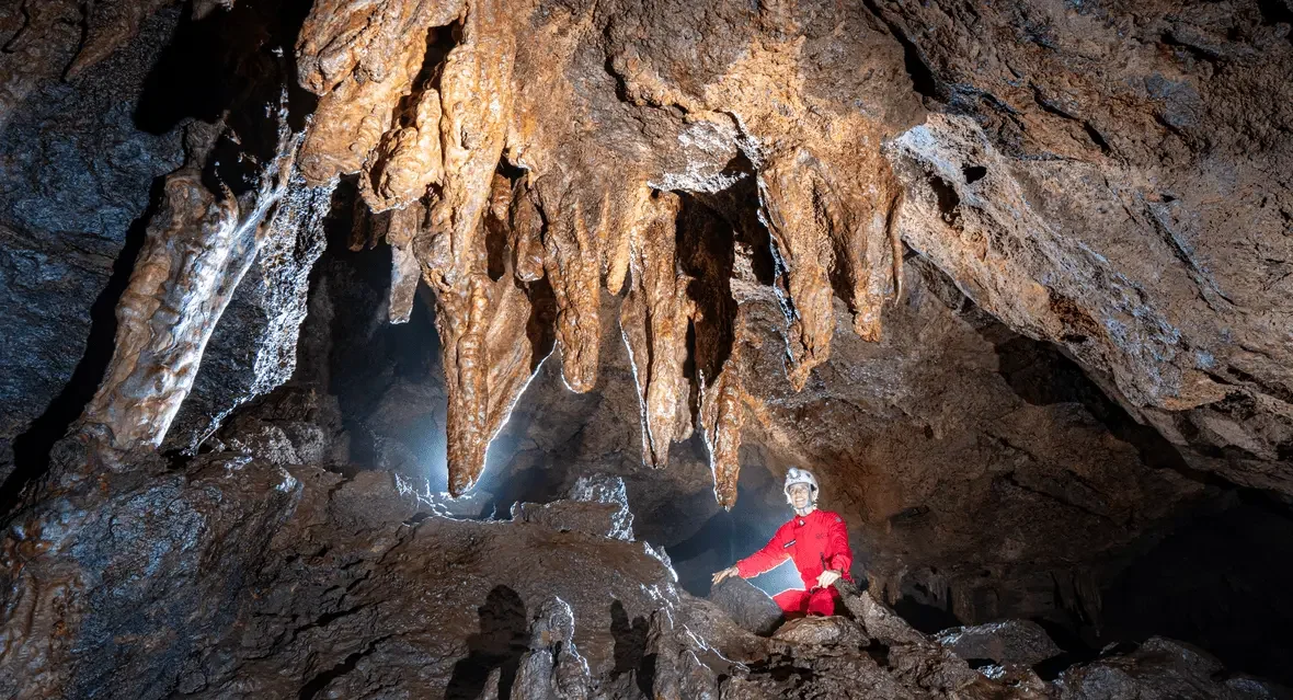 Caverna no corpo mineral de S11B na Floresta Nacional de Carajás, destaque para formações rochosas e uma pessoa explorando com luz. Foto: Daniel Menin