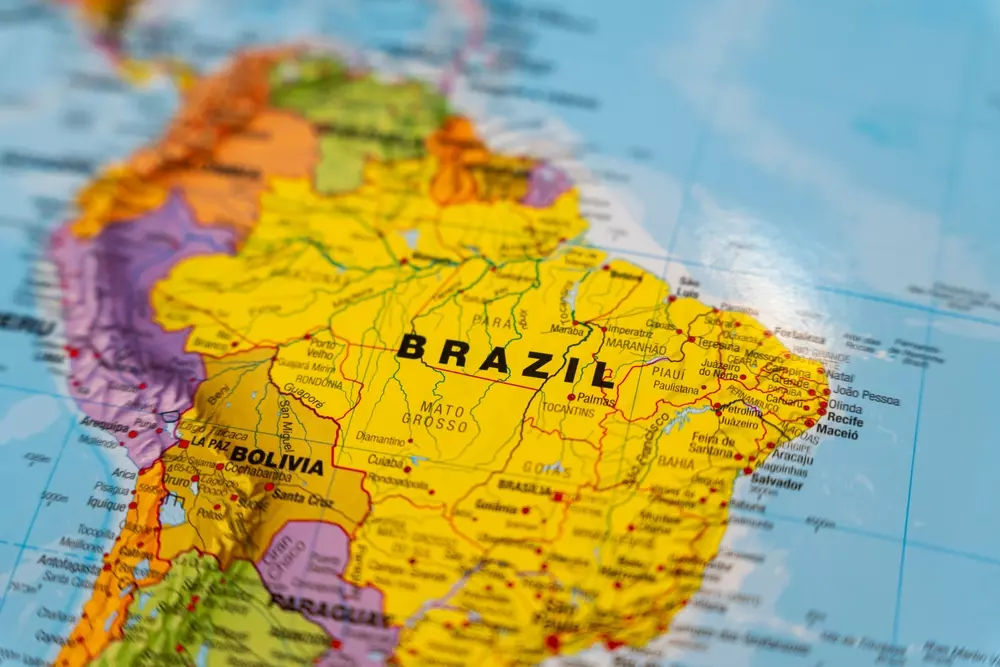 Mapa-múndi destacando o Brasil em destaque na América do Sul, com detalhes das fronteiras e principais regiões brasileiras, com foco em sua localização geográfica.