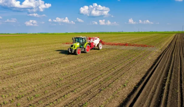 Trator agrícola aplicando fertilizantes em uma plantação extensa