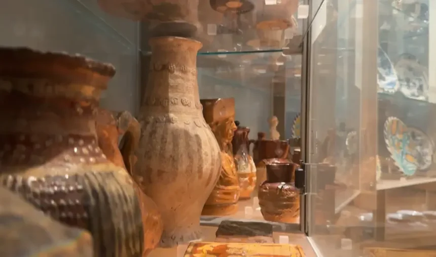 Vasos antigos de cerâmica com texturas rústicas e jarras esculpidas expostos em uma vitrine de vidro