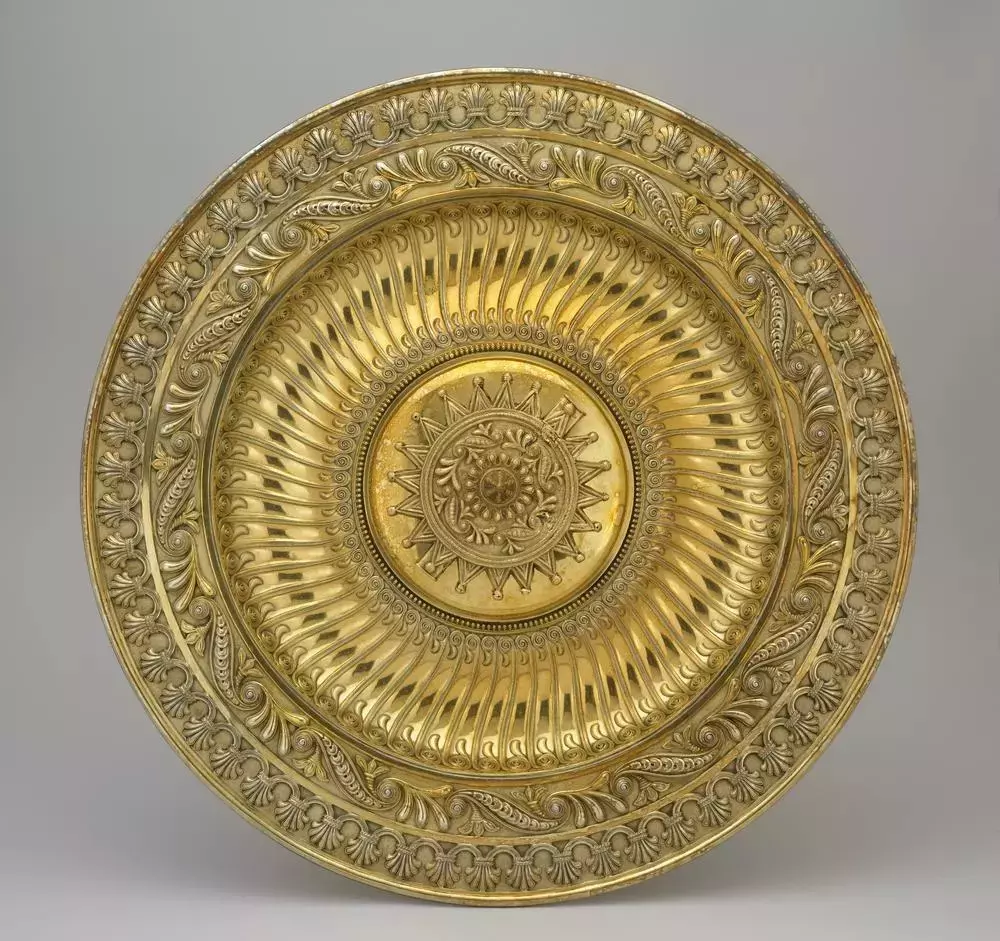 Prato ornamental em ouro de Asante exibindo relevos detalhados e padrões circulares