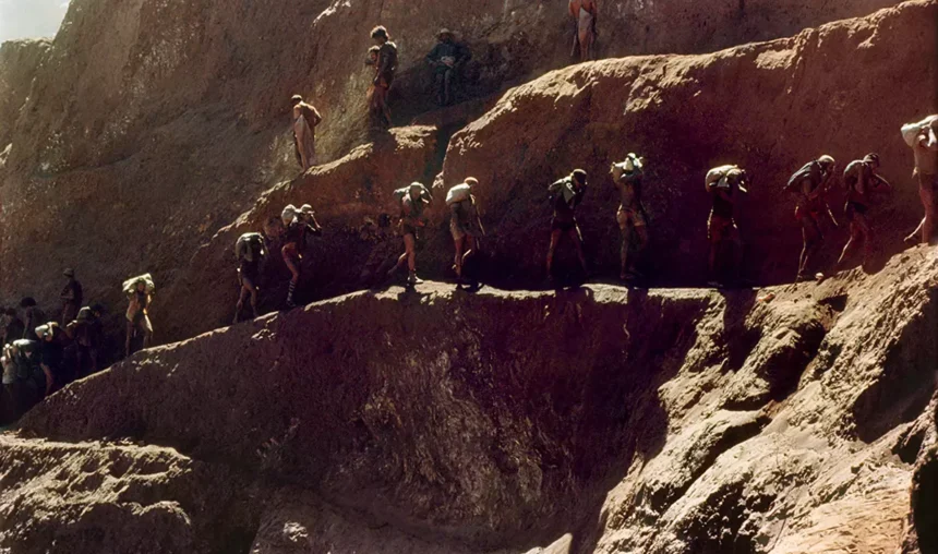 Mineração em Serra Pelada em 1981, com milhares de operários trabalhando na lavra de ouro em uma paisagem de rochas e escadas de acesso.