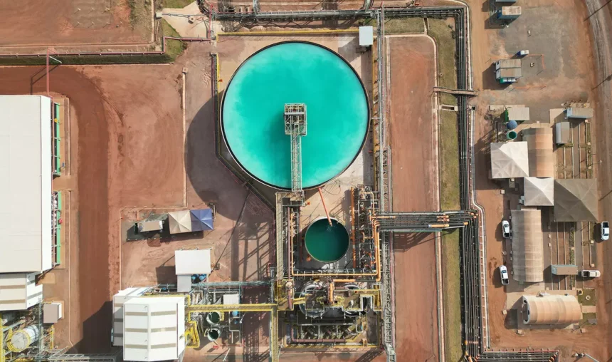 Instalações da Serra Verde Pesquisa e Mineração vistas de cima, destacando tanques de processamento e dutos sobre a terra vermelha.
