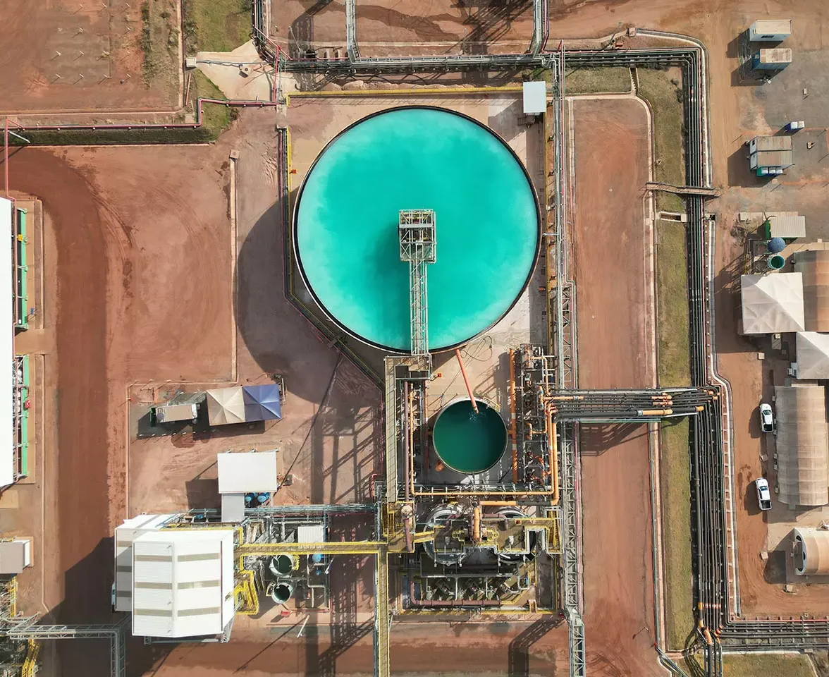 Instalações da Serra Verde Pesquisa e Mineração vistas de cima, destacando tanques de processamento e dutos sobre a terra vermelha.