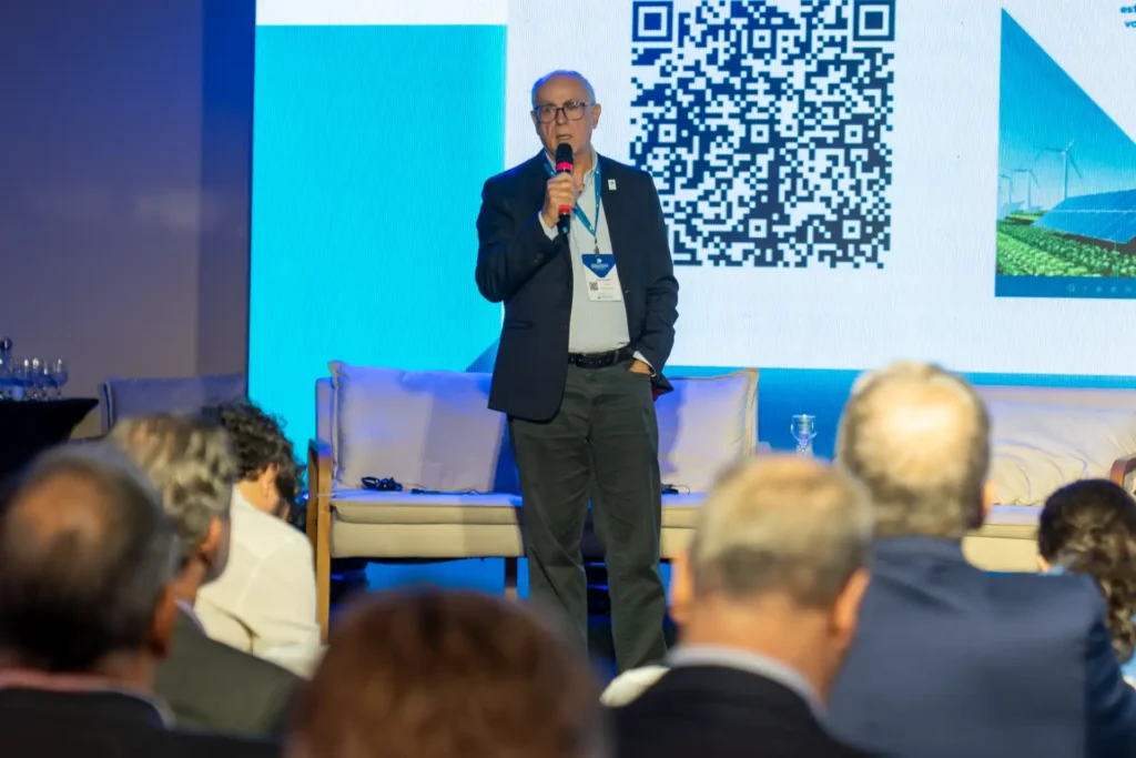 Júlio Nery, diretor de Assuntos Minerários do Ibram, palestrando em evento com microfone ao lado de telão com QR code ao fundo e público em auditório