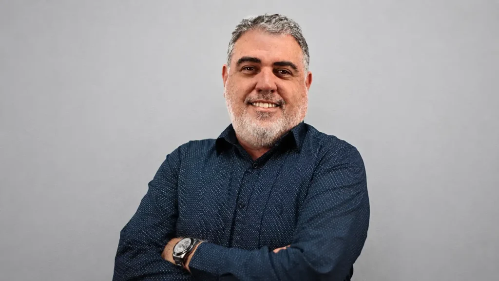 Retrato de Leonardo Braga, gerente sênior de operação e manutenção da Alunorte, sorrindo com os braços cruzados, em estúdio com fundo cinza claro.