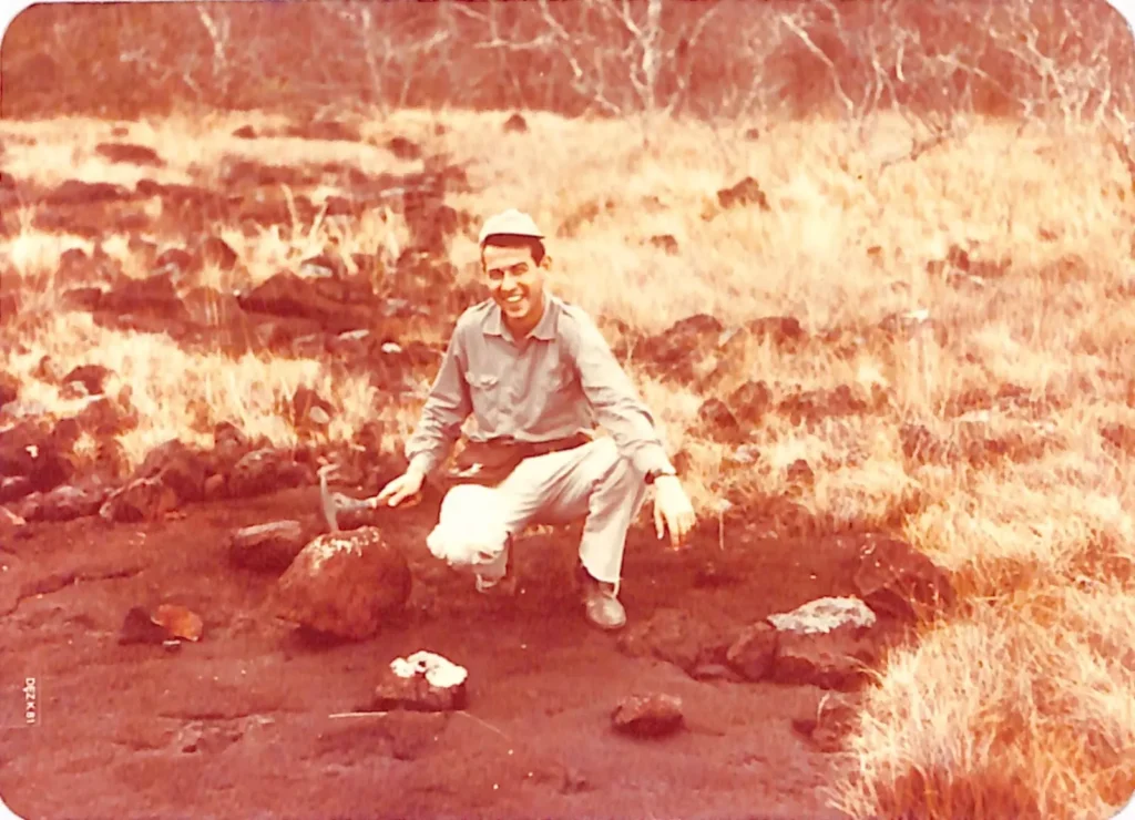 Breno Santos com o martelo de ge&oacute;logo entre blocos de min&eacute;rio de ferro em clareira de Caraj&aacute;s, nos anos 60
